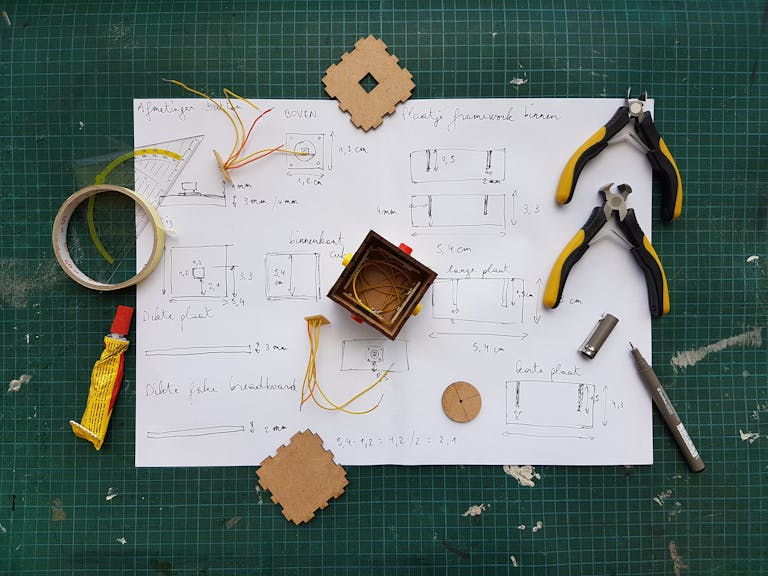 Overhead view of DIY electronics project with components and tools on grid mat.
