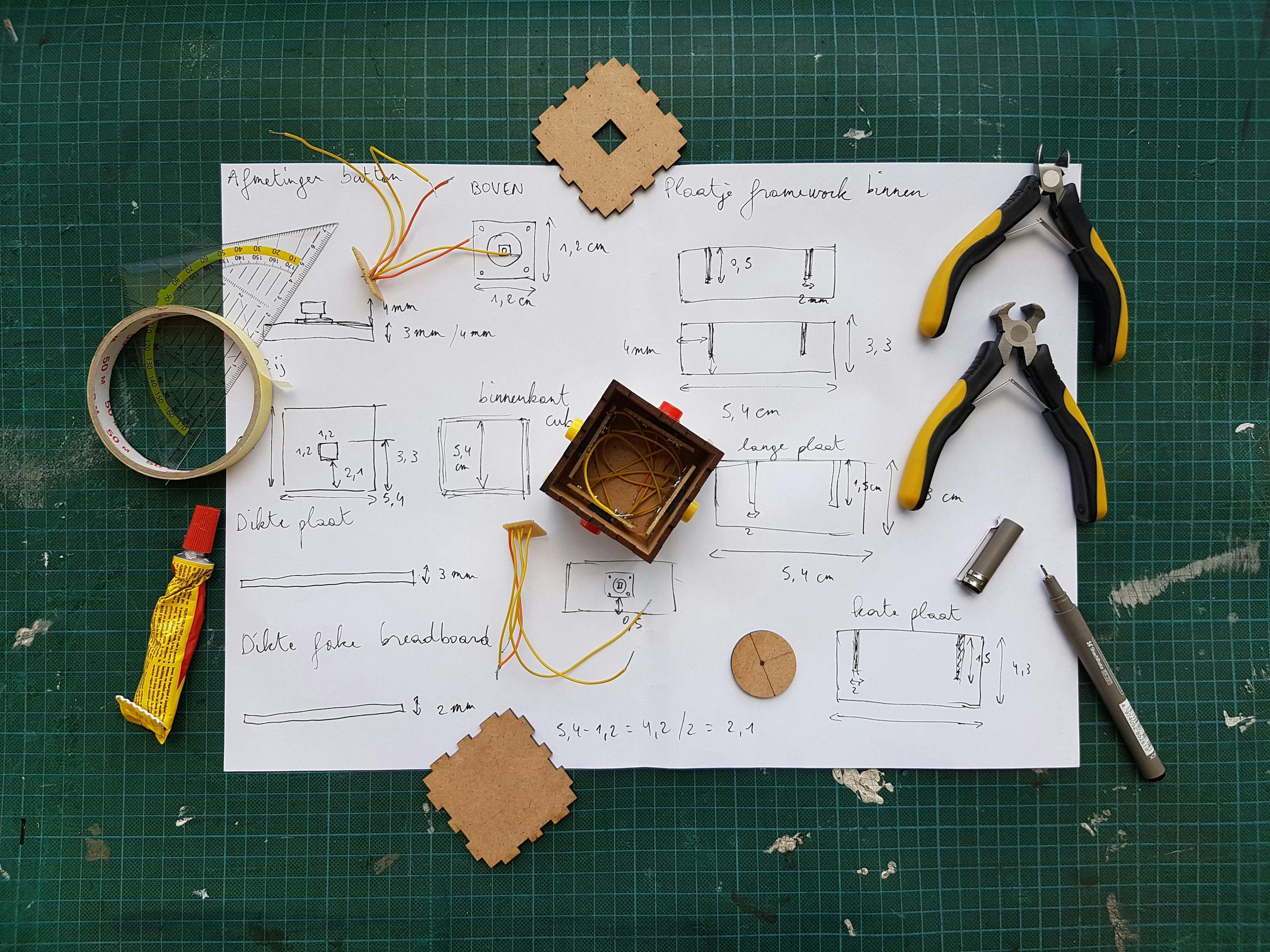 Overhead view of DIY electronics project with components and tools on grid mat.